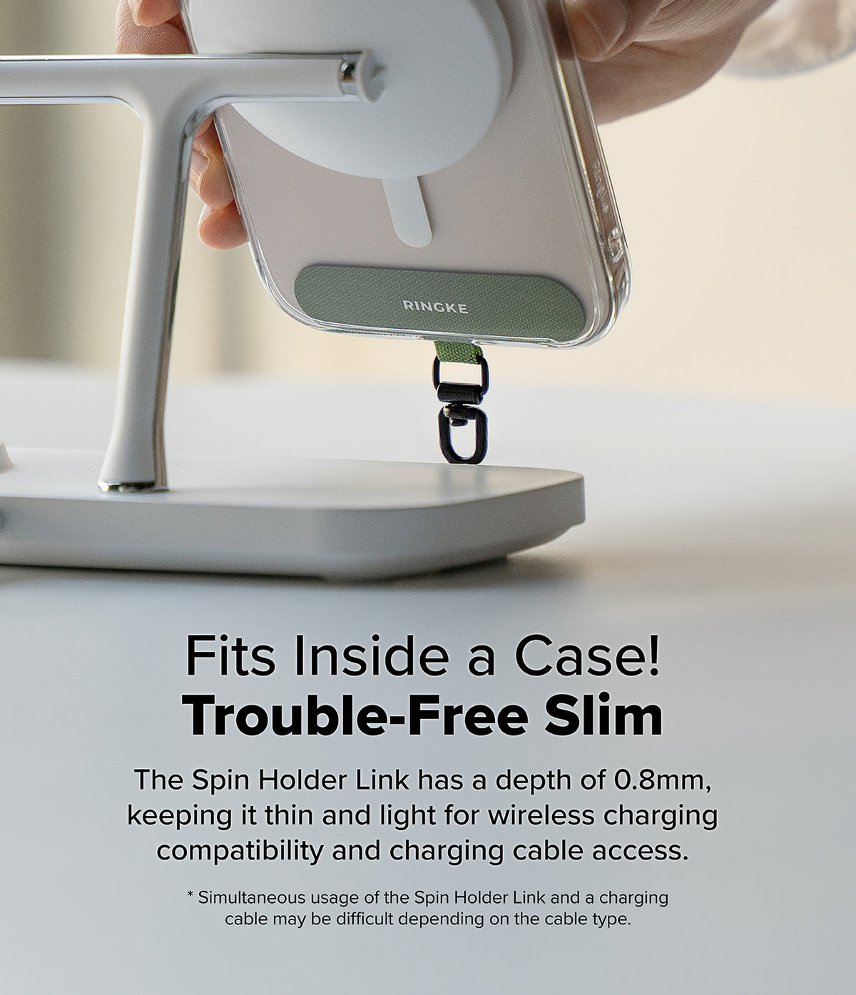 Holder Link Spin - A slim green phone tether tab attached to a smartphone case while mounted on a wireless charging stand.