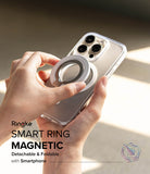Ringke Smart Ring Magnetic - Hands holding a smartphone with a detachable, foldable magnetic ring attached to the back.
