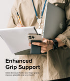 Card Holder | Stand Slot - Person holding a smartphone with a black magnetic card holder acting as a finger grip while carrying a laptop.