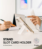 Card Holder | Stand Slot - A smartphone with a white adhesive stand and card holder attached, propped up on a desk.
