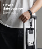 Holder Link Tactical Webbing Hand Strap - A person in a white t-shirt and black pants holds a silver rolling suitcase, with a clear phone case attached to a black wrist strap hanging from the handle. White text on the left reads 'Have a Safe Journey'.