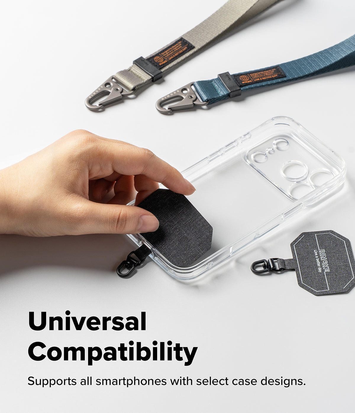 Holder Link Tactical Webbing Hand Strap - A clear smartphone case with a black textured magnetic patch and black carabiner clip is shown being held by a hand. Two additional strap-style phone accessories in gray and blue are placed above on a white background, along with a black branded tag.