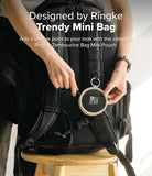Mini Pouch | Tambourine Bag - Hands attaching a small, round, beige and black Ringke pouch to a black backpack strap.