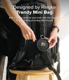 Mini Pouch | Tambourine Bag - Hands attaching a small, round black Ringke pouch to the strap of a black backpack.