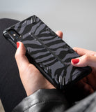 iPhone XS Max Case | Dual-X Design - Hands holding a phone with a black and grey zebra-patterned protective case.