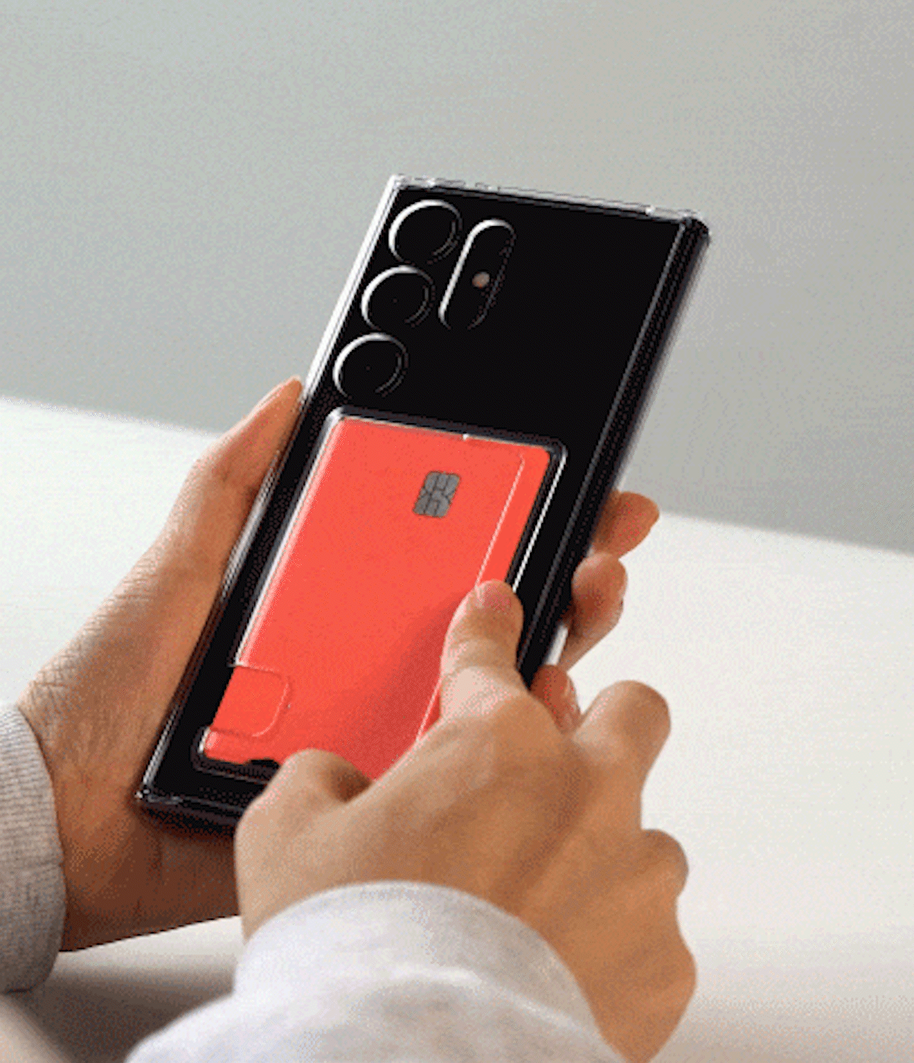 Galaxy S25 Ultra Case | Fusion Card - Hands sliding a red credit card into the back slot of a clear phone case.