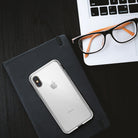 iPhone X Case | Fusion - Clear iPhone X case on a black notebook next to a laptop and orange-rimmed glasses.