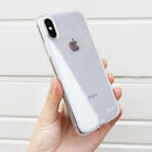 iPhone X Case | Air - A hand holding an iPhone X in a clear, slim protective case against a white slatted background.