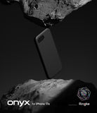 iPhone 17e Case | Onyx - A black phone case suspended between two rough, dark stone surfaces against a moody background.