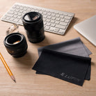 Microfiber Cleaning Cloth [Large] - Black and grey microfiber cloths with Lupin branding on a wooden desk with camera lenses.