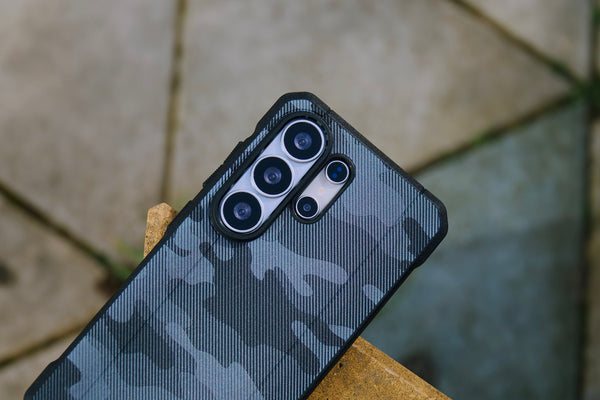 A hand holding samsung galaxy smartphone covered with camo case