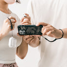 Paracord Lanyard Wrist Strap [6 Pack] - Two people wearing black and red paracord wrist straps attached to a phone and case.