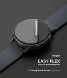 Galaxy Watch Active | Easy Flex - A clear screen protector film being applied to a black Galaxy Watch Active on a dark background.