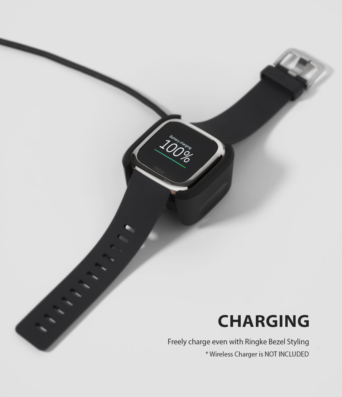 Fitbit Versa 2 | Bezel Styling 01 - Smartwatch with silver bezel styling charging on a black dock showing 100% battery.