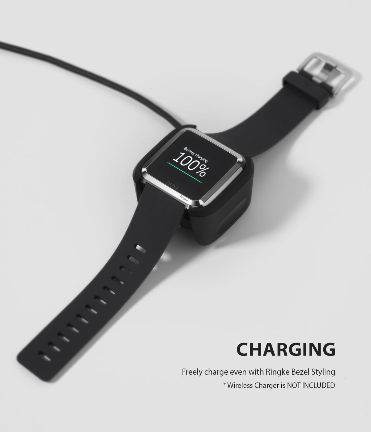Fitbit Versa | Bezel Styling 01 - A Fitbit Versa with a silver bezel accessory charging on a dock, showing 100% battery.