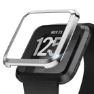 Fitbit Versa | Bezel Styling 01 - A metallic silver bezel accessory hovering above a black Fitbit Versa smartwatch.