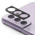 Galaxy S21 FE | Camera Styling - Black adhesive camera lens protector hovering above the triple-lens array of a lavender smartphone.